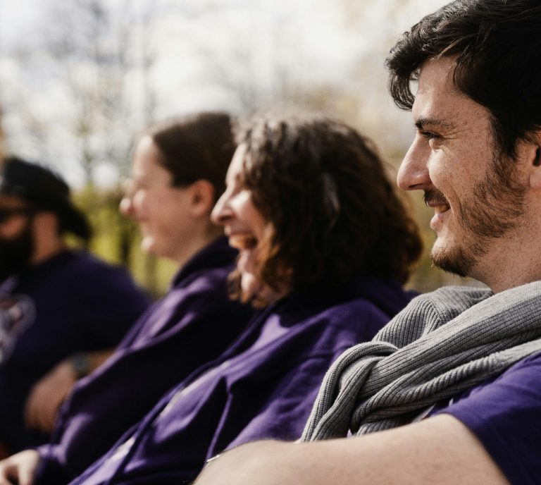 Erwachsene Menschen sitzen und lachen bei einer Reflexionsrunde während eines Teamevents.