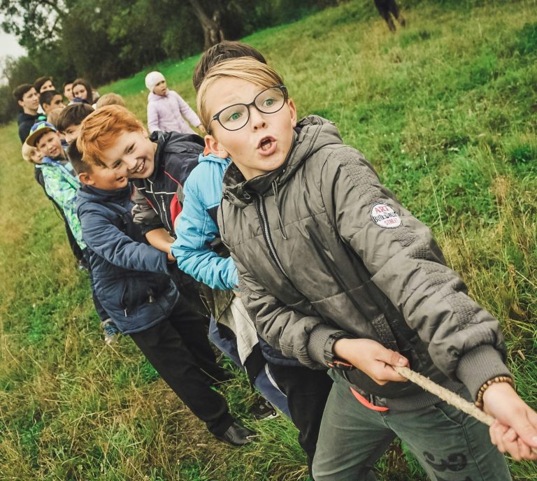 Eine Schulklasse macht Tauziehen, Kinder lachen und arbeiten als Team