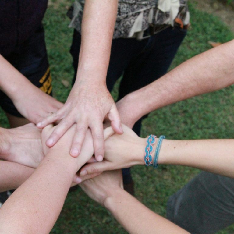 Hände die in der Mitte eines Kreises aufeinander liegen, um sich viel Erfolg zu wünschen